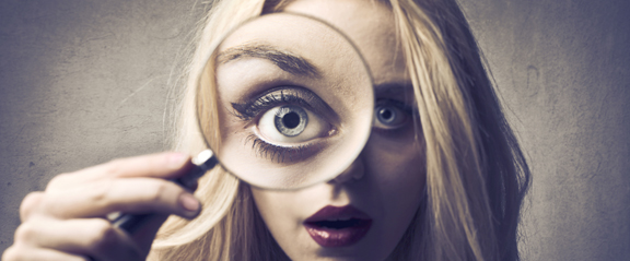 Beautiful woman looking through a magnifying glass